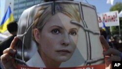 A supporter of former Ukrainian Prime Minister Yulia Tymoshenko hold posters depicting her during a rally outside the Appellate Court in Kiev, Ukraine. (file photo)