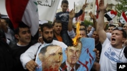 Syrian protesters shout slogans as they burn a poster of Syrian President Bashar Assad, left, and his father Hafez Assad during a demonstration in front of the Syrian embassy, in Nicosia, Cyprus, April 22, 2011. 