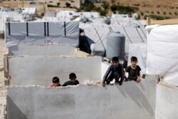 Syrian refugees children climb a concrete wall at a refugee camp in the eastern Lebanese border town of Arsal, Lebanon, Aug. 5, 2019.