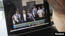 A woman watches a CCTV video showing Gu Kailai being escorted into the court room at Hefei Intermediate People's Court, August 9, 2012.