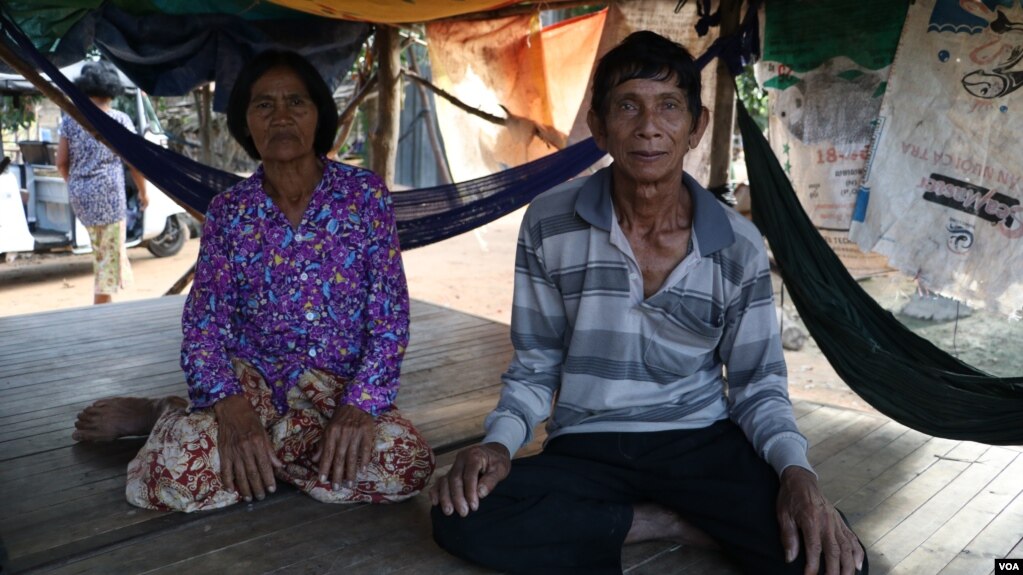 លោក ចេក ឈុន និងអ្នកស្រី ហ៊ុល វន់ ជាឪពុកម្តាយរបស់លោក ឈុន វាន អង្គុយនៅលើគ្រែខាងមុខផ្ទះ ក្នុងភូមិតាប៉ោ ឃុំក្តីរុន ស្រុកពួក ខេត្តសៀមរាបផ្ទះ។ (ស៊ុន ណារិន/VOA)