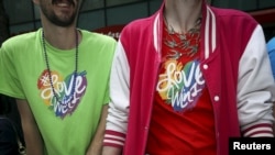 FILE - Two men wearing shirts with "#LoveWins" written on them watch the 2015 San Francisco gay pride parade.
