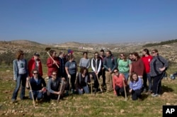 American rabbinical students take a group photo, with the village of Attuwani in the background, during a day planting olive trees, near Hebron in the West Bank, Jan. 25, 2019.