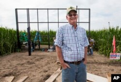 In this July 29, 2017 photo, corn farmer Jim Carlson of Silver Creek, Ne., waits to be interviewed by a television reporter while standing in front of solar panels he is building on his land in the proposed path of the Keystone XL pipeline.