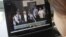 A woman watches a CCTV video showing Gu Kailai being escorted into the court room at Hefei Intermediate People's Court, August 9, 2012.