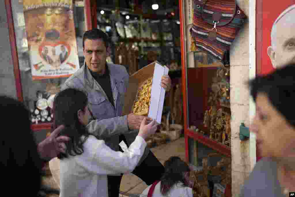 A salesperson speaks to visitors next to the Church of the Nativity, traditionally believed to be the birthplace of Jesus, in the West Bank city of Bethlehem, Dec. 25, 2024.