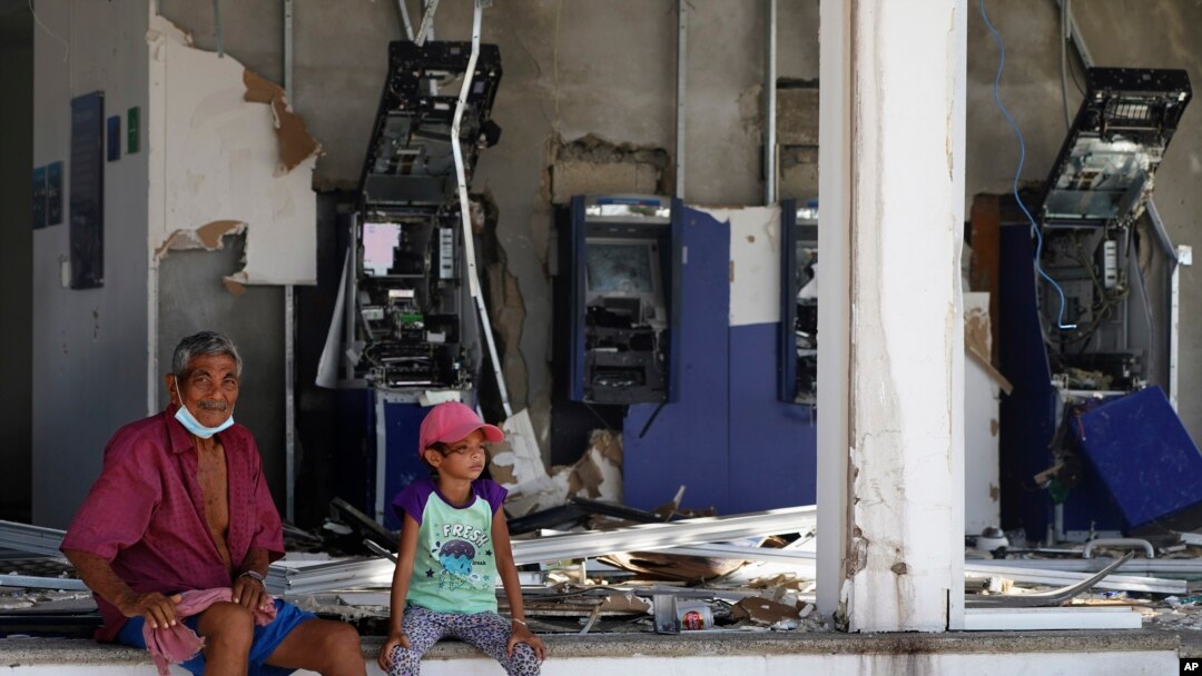 Residentes sentados delante de una entidad bancaria, sin ventanales y con los cajeros destrozados, dos días después del paso del devastador huracán Otis, de categoría 5, en Acapulco, México, el viernes 27 de octubre de 2023. 