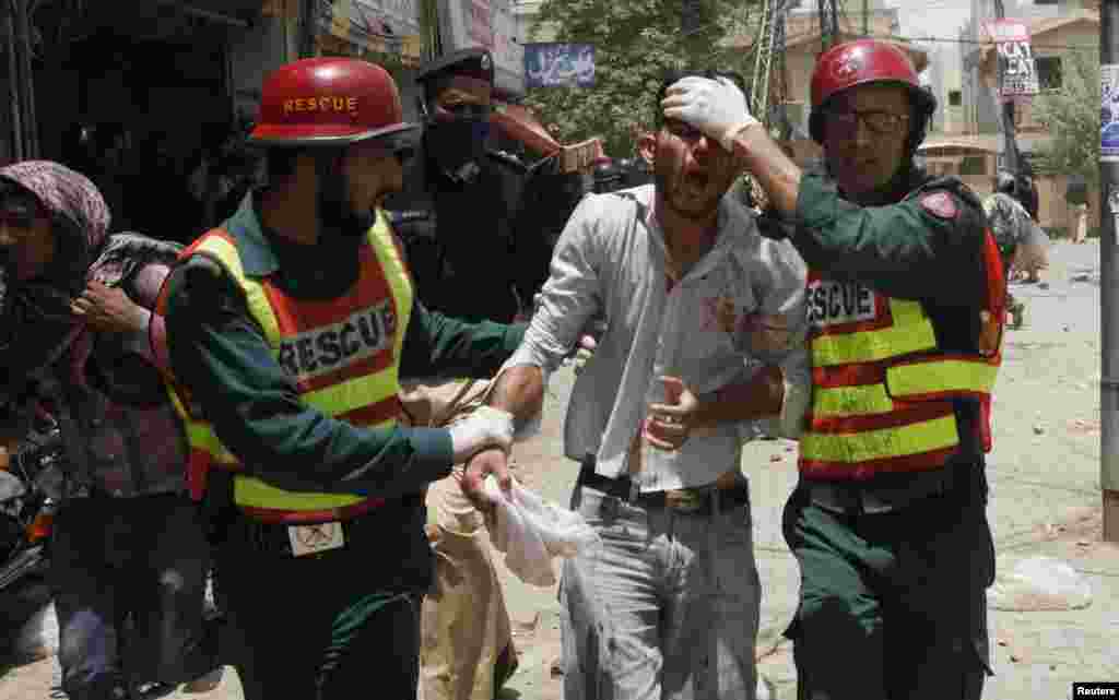 Rescue workers assist an injured supporter of Tahir-ul Qadri of the political party Pakistan Awami Tehreek, during a protest in Lahore, June 17, 2014.