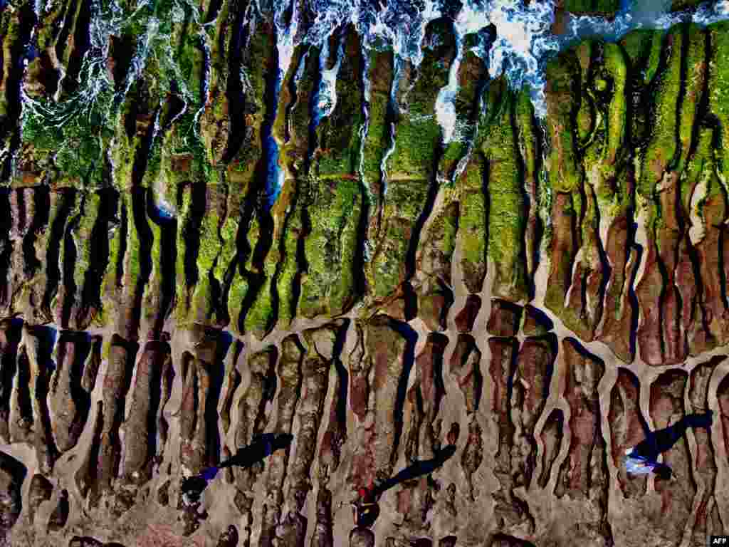 This aerial photo shows people walking across Green Reef, covered in algae, in Laomei on the northern coast of Taiwan, Taiwan.