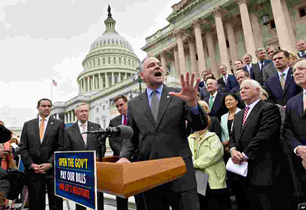 Sen. Tim Kaine, center, speaks as Senate Democrats gather outside the Capitol to urge Speaker of the House John Boehner, R-Ohio, and other House Republicans, to break the impasse on a funding bill and stop the government shutdown that is now in its second week, Oct. 9, 2013, in Washington, D.C.