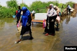 People carry their belongings as they wade through flood waters near the River Nile, on the outskirts of Khartoum, Sudan, Sept. 2, 2019.