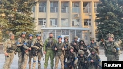 重新夺回利曼的乌军士兵在一座楼前合影留念。
