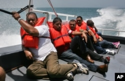 FILE - En route to a processing center on mainland Puerto Rico about three hours away, Cuban migrants picked up earlier on Puerto Rico's remote Mona Island sit on the deck of a U.S. Border Patrol boat, June 13, 2006.