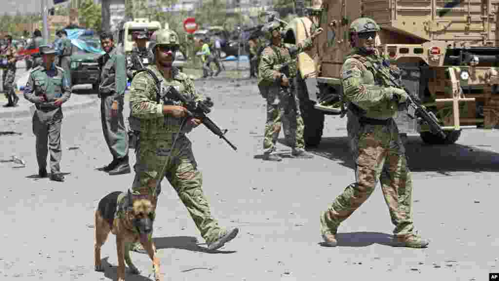 NATO and Afghan security forces walk at the site of a suicide attack in Kabul, Afghanistan, Aug. 10, 2014. 