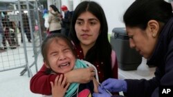 A Venezuelan girl cries while receiving a measles vaccine at an immigration processing office on the Rumichaca bridge, after crossing the border from Colombia to Ecuador, June 13, 2019.