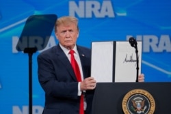 U.S. President Donald Trump holds up an executive order with his signature as he announces that the United States will drop out of the Arms Trade Treaty signed during the Obama administration during a speech in Indianapolis, Indiana, April 26, 2019.