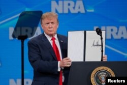 U.S. President Donald Trump holds up an executive order with his signature as he announces that the United States will drop out of the Arms Trade Treaty signed during the Obama administration during a speech in Indianapolis, Indiana, April 26, 2019.