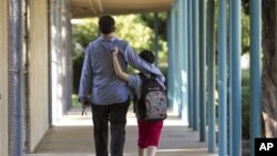 FILE - In this 2012 photo, a father walks his son, who is autistic, to the Nestle Avenue Elementary School in Los Angeles.