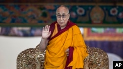 FILE - Tibetan spiritual leader the Dalai Lama gestures to devotees before he starts teaching on the fifth day of Kalachakra near Leh, India.