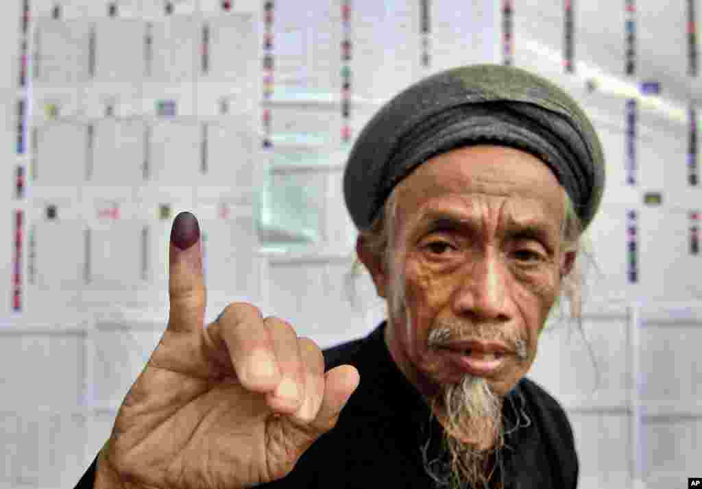 A member of the An-Nadzir Muslim group shows his inked finger after casting his ballot at a polling station during the parliamentary election in Gowa, South Sulawesi, Indonesia, April 9, 2014.