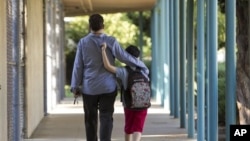 FILE - In this 2012 photo, a father walks his son, who is autistic, to the Nestle Avenue Elementary School in Los Angeles.