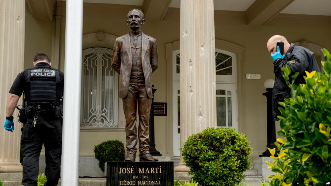 Lubang-lubang bekas peluru tampak di tiang di belakang patung pahlawan kemerdekaan Kuba, José Martí, sementara penyelidik keamanan federal AS menyelidiki serangan dari seorang pria bersenjata di Kedutaan Besar Kuba di Washington D.C, 30 April 2020.