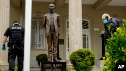 Bullet holes are visible on a column behind a statue of Cuban independence hero José Martí as Secret Service officers investigate after police say a person with an assault rifle opened fire at the Cuban Embassy, April 30, 2020, in Washington.