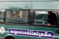 FILE - Yeang Sothearin and Uon Chhin, former journalists for U.S. founded Radio Free Asia (RFA), sit inside a police vehicle as they arrive for a bail hearing at the Appeals Court in Phnom Penh, Cambodia, April 19, 2018.