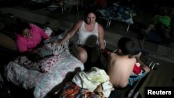 People rest at a makeshift camp outside their apartment building after an earthquake in Yauco, Puerto Rico