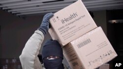 A member of the Connecticut National Guard carries boxes of COVID-19 test kits bound for nursing homes in Windsor Locks, Conn., Jan. 21, 2022 at Camp Hartell in Windsor Locks, Connecticut.