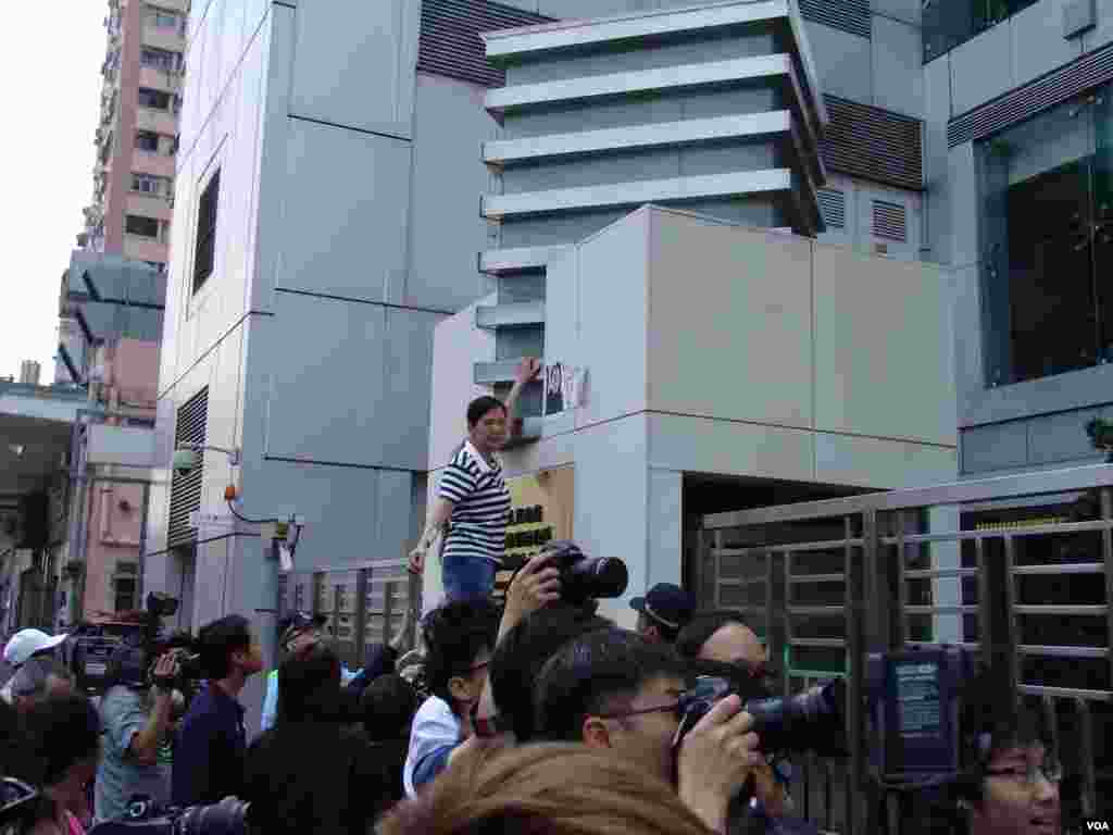 社会民主连线一成员将刘霞照片和抗议标语贴在中联办大门墙上（美国之音海彦拍摄)