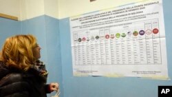 A woman looks at a candidates' list for Emilia-Romagna region elections, at a polling station in Bologna, Italy, Jan. 26, 2020. 