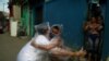 Teacher Maura Silva, who created a "hug kit" using plastic covers, embraces her student Yuri Araujo Silva at Yuri's home, amid the coronavirus disease (COVID-19) outbreak. Source: Pilar Olivares (Reuters)