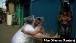 Teacher Maura Silva, who created a "hug kit" using plastic covers, embraces her student Yuri Araujo Silva at Yuri's home, amid the coronavirus disease (COVID-19) outbreak. Source: Pilar Olivares (Reuters)