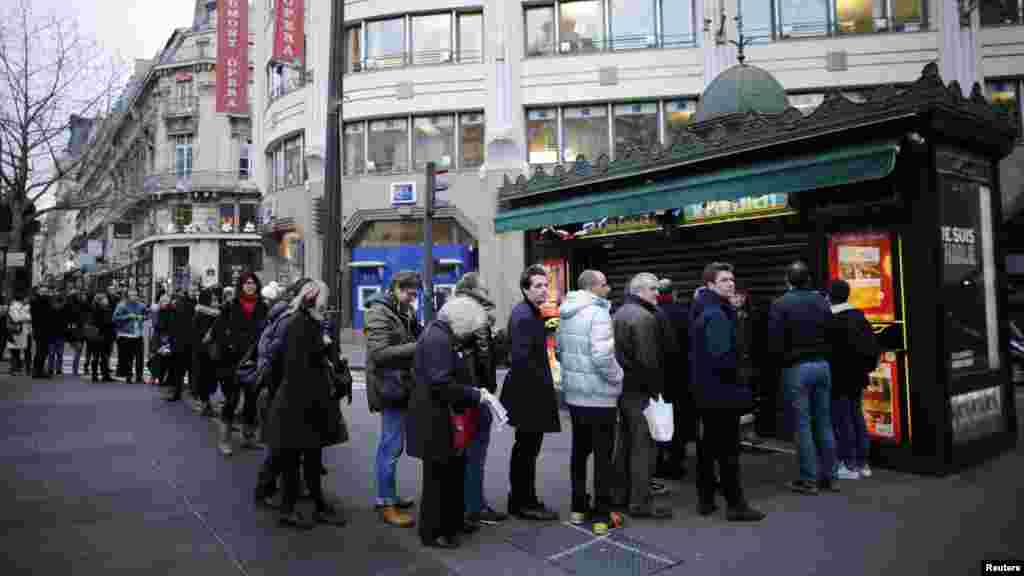 People queue to get a copy of satirical French magazine Charlie Hebdo new issue titled "Tout est pardonne" ("All is forgiven") showing a caricature of Prophet Mohammad in front of a kiosk in Paris, Jan. 14, 2015. 