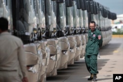 FILE - A Cambodian police officer watches buses donated by China to Cambodia during a handover ceremony in Phnom Penh, July 13, 2017.