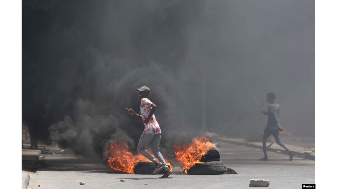 Somali demonstrators run past burning tires during protests sparked by the killing of a rickshaw driver and passenger in Mogadishu, Somalia, April 13, 2019.