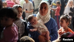 (FILE) A displaced Palestinian mother carries her daughter Lynn as she waits to get her vaccinated against polio, in Deir Al-Balah, in the central Gaza Strip September 1, 2024.