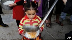 In this Jan. 23, 2016, photo, a displaced girl waits for donated food at al-Takia camp in Baghdad, Iraq. More than 3 million Iraqis are displaced within the country by violence and instability.