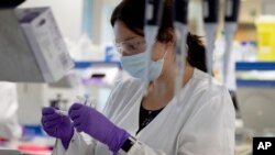 资料照片:强生公司旗下比利时杨森制药公司实验室的研究人员今年6月在研制新冠病毒疫苗期间观察试管。