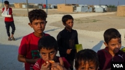 Young boys play and eat around the market area in al-Hol Camp, Northeast Syria, where more than 40,000 people believed to be part of IS are still held, on Oct. 12, 2024. (Yan Boechat/VOA)