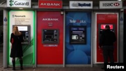 FILE - People withdraw Turkish liras from automatic teller machines in Istanbul, October 17, 2011. 