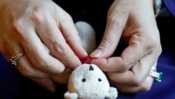 A Massachusetts resident identifying herself only as Safi, who asked that her last name not be used for fear of retribution against her relatives in Afghanistan, ties a bow around a keepsake teddy bear Nov. 9, 2021.