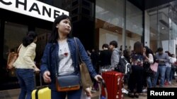 FILE - Mainland Chinese visitors wait outside a luxury store at a shopping district in Hong Kong.