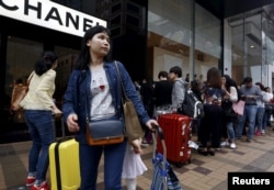 FILE - Mainland Chinese visitors wait outside a luxury store at a shopping district in Hong Kong.