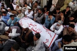 FILE - Shiite Muslim men from Pakistan's ethnic Hazara minority mourn around the coffins of their relatives, who were killed in a shooting, in Quetta, Pakistan, Oct. 9, 2017.