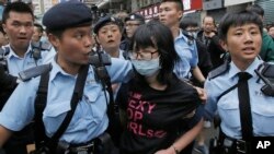 A protester is taken away by police officers after the confrontation between activists demonstrating against mainland Chinese shoppers and local villagers at a suburban district of Yuen Long in Hong Kong, Sunday, March 1, 2015.