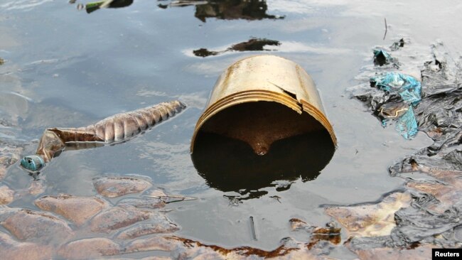 FILE - Crude oil from a Shell pipeline spill accumulates along a riverbank in the Oloma community in the Niger Delta, Nov. 27, 2014.