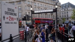 Commuters wearing face coverings due to Covid-19, enter Oxford Circus London Underground station in central London on June 7, 2021. - The Delta variant of the coronavirus, first discovered in India, is estimated to be 40 percent more transmissible…