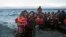 A woman screams for help after she and her daughter fell in the water as they arrive along the northeastern Greek island of Lesbos,  Oct. 2 , 2015. 